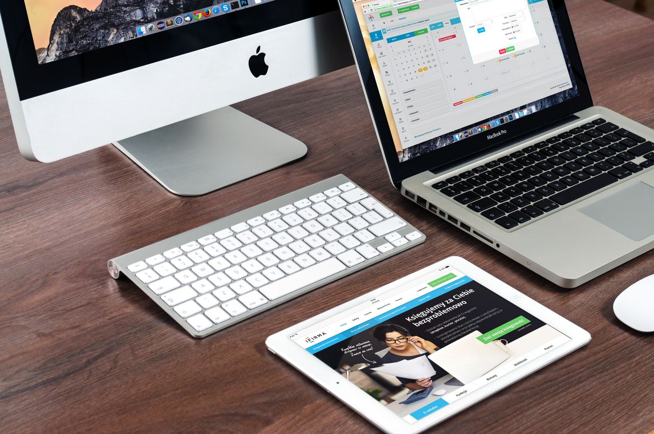 A streamlined office desk arrangement showcasing Apple devices: iMac, MacBook, and iPad.